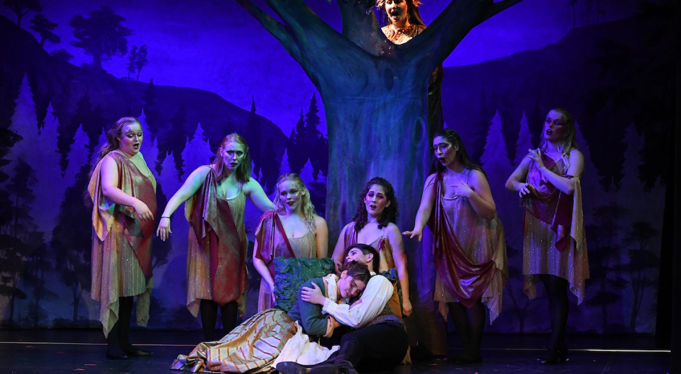 Cinderella and prince charming embrace under a tree of nymphs during the opera performance of Cinderella