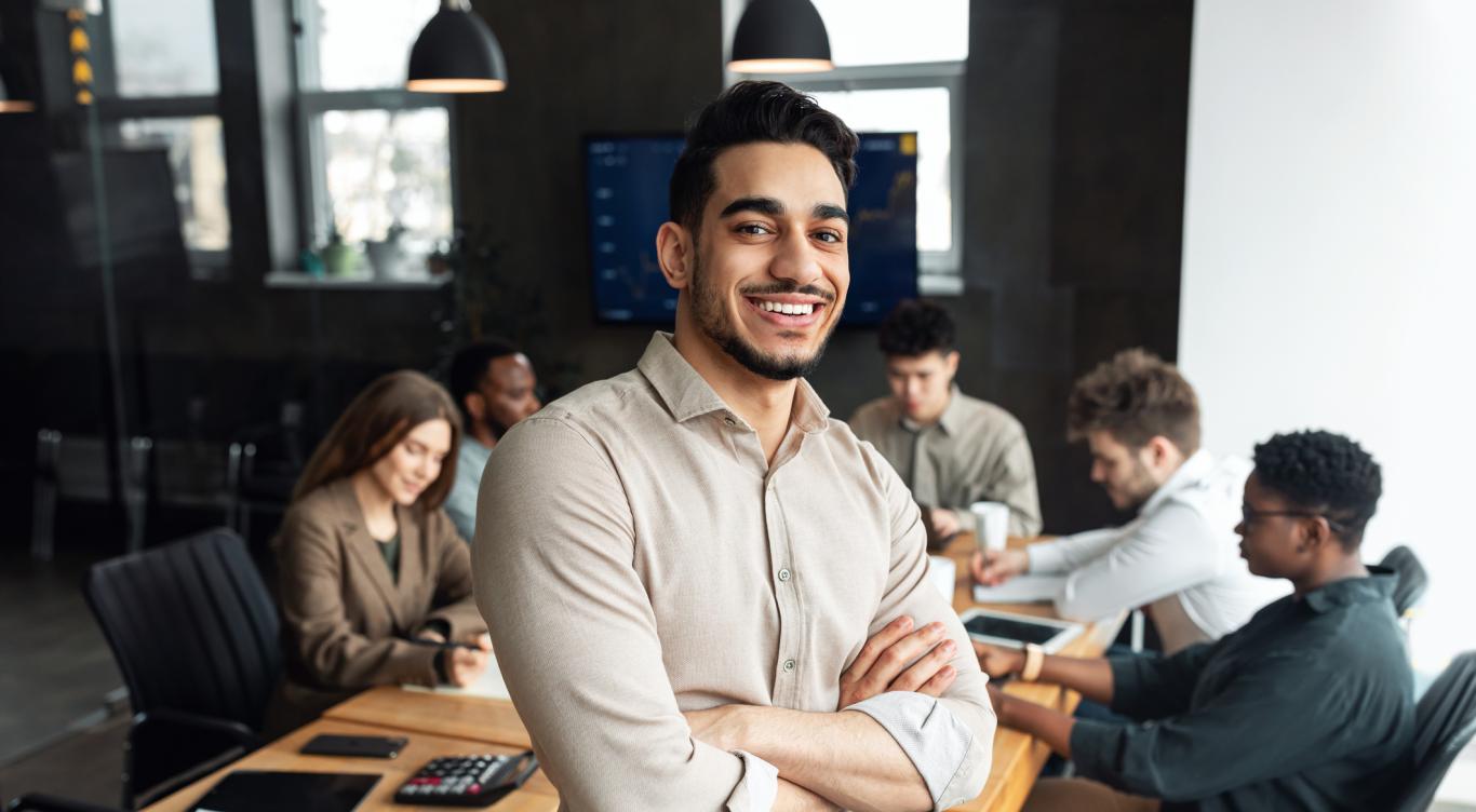 Young businessman sitting on desk and posing