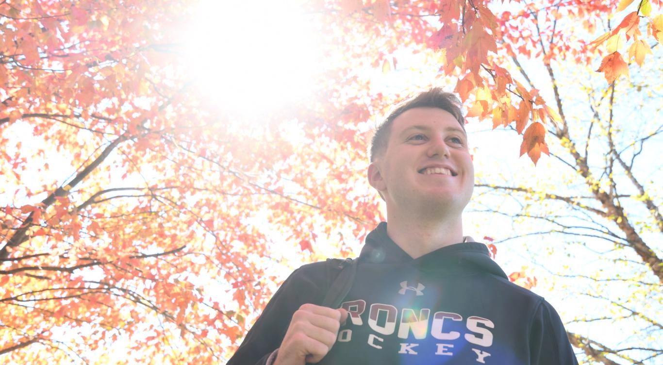 Student walks under fall leaves