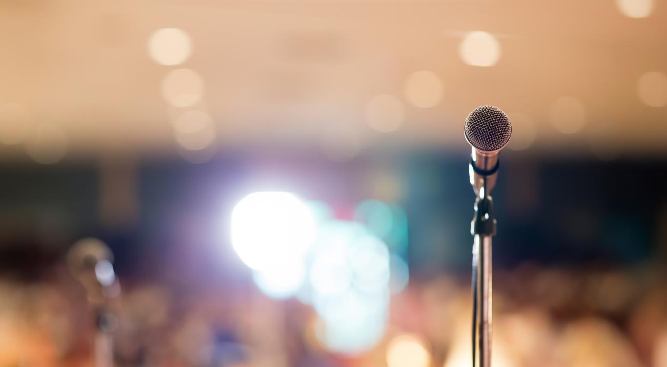 image of a microphone in front of an audience