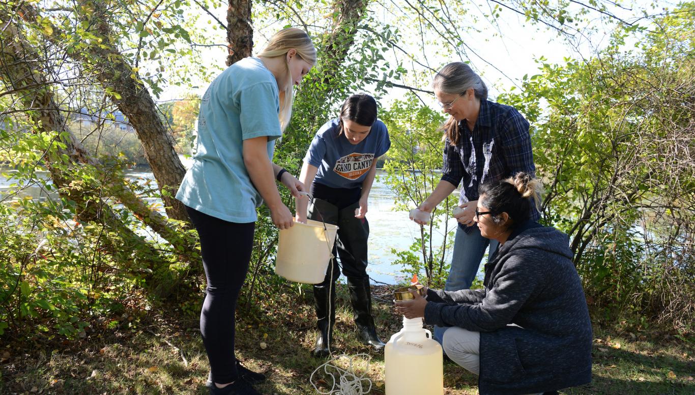 Group of students getting samples of water outdoors