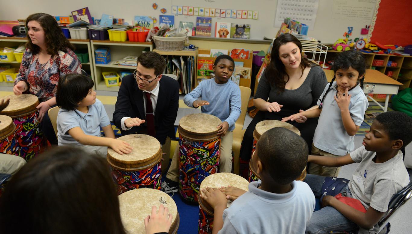 Students in a classroom playing drums.