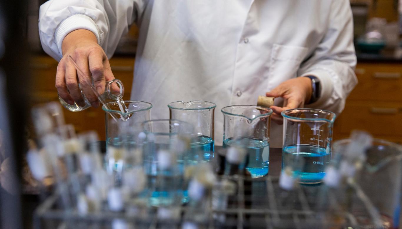 Person in lab coat with test tubes