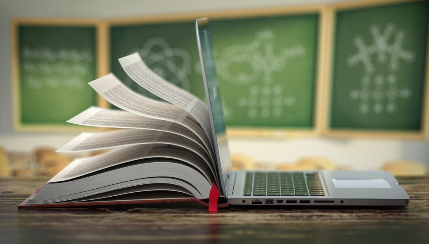 Book mingled with laptop in classroom