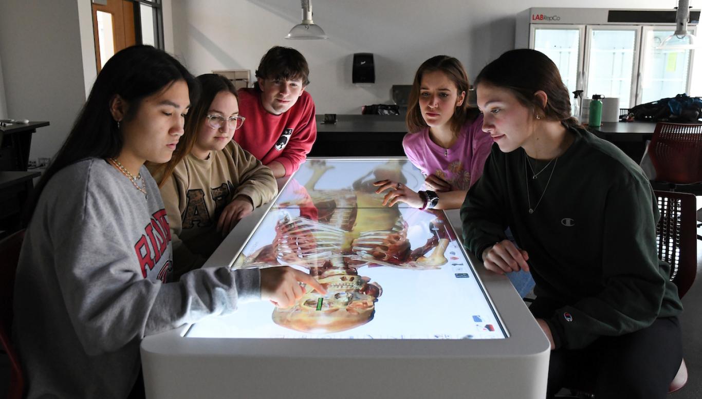 Students gather around screen displaying a human skeleton