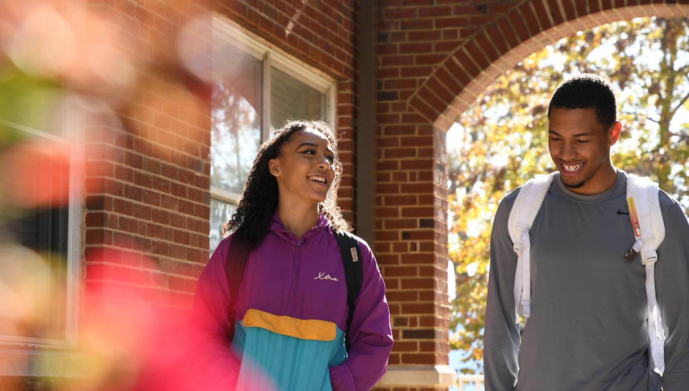 Two students walk and laugh on campus