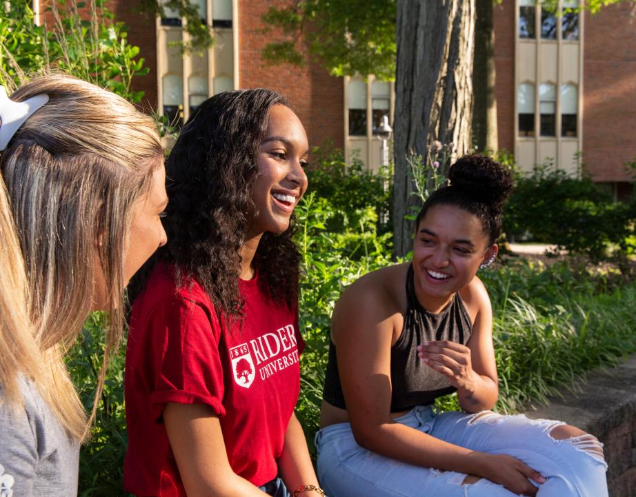 Three students talk and laugh together