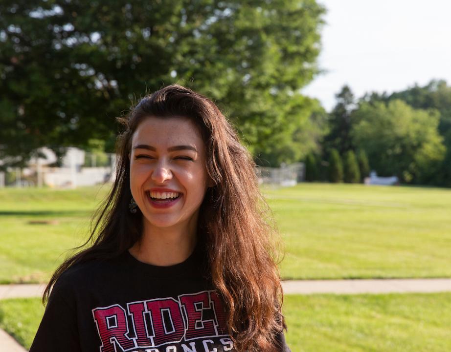Student smiles for photo on campus green.
