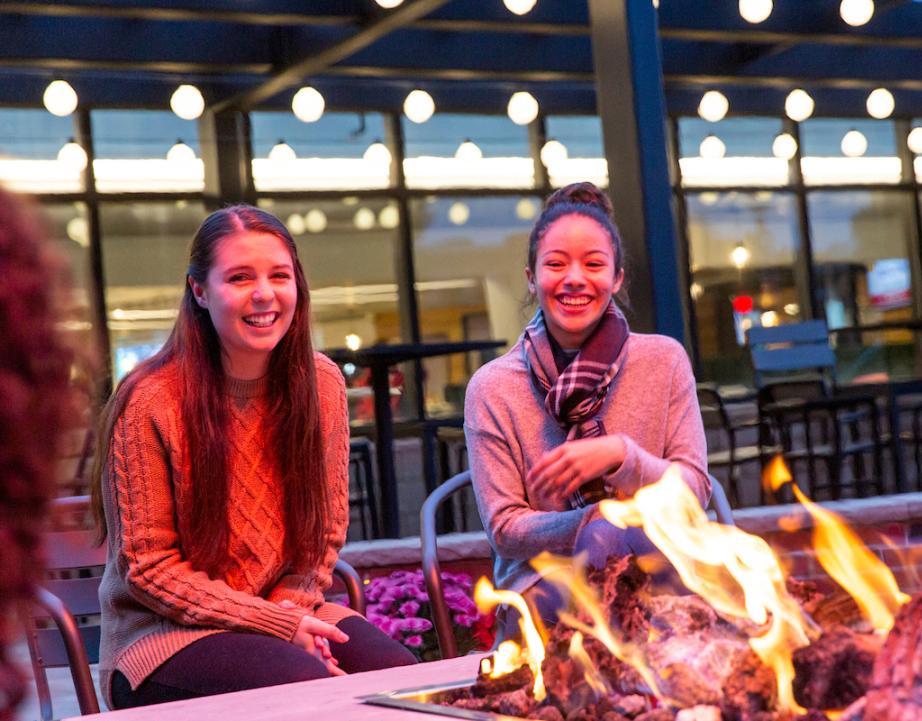 Students sit around the fire pit and laugh.