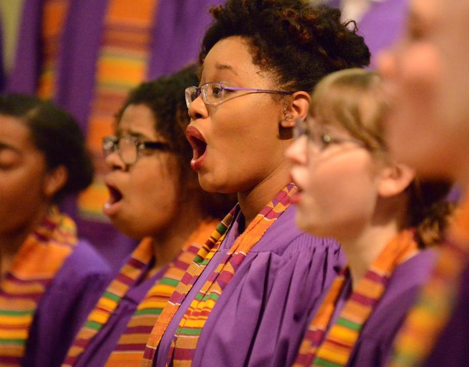 Group of female choral students dressed in vibrant colored robes