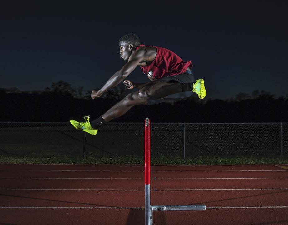Division I athlete jumps hurdle on track