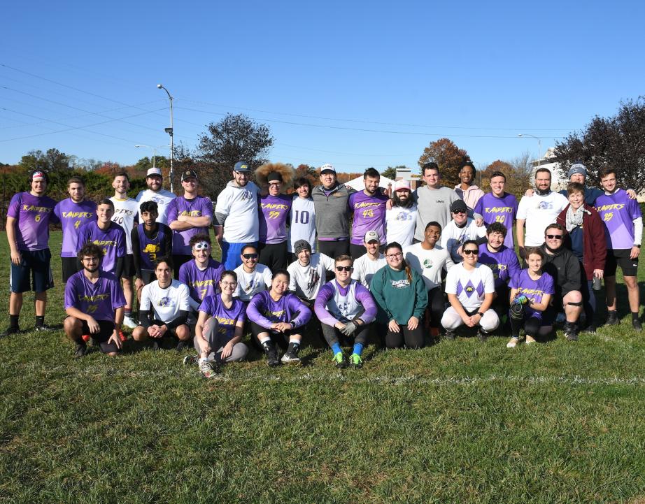 Large group of alumni pose for photo on field