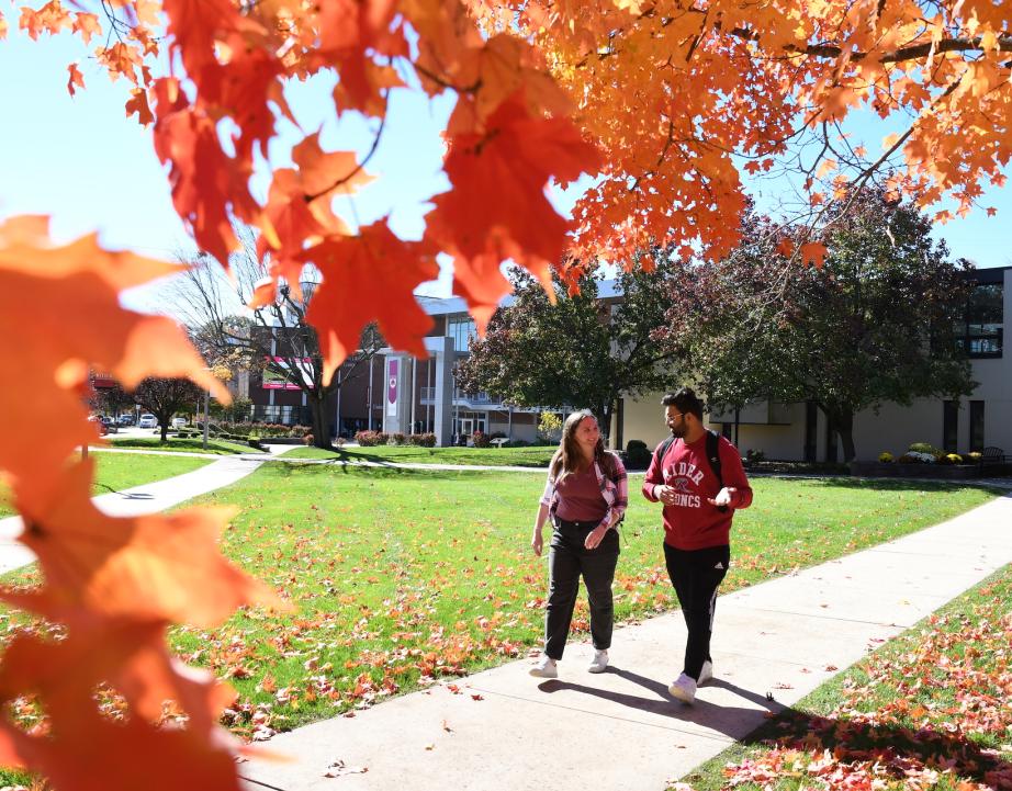 Two students walk on campus in fall