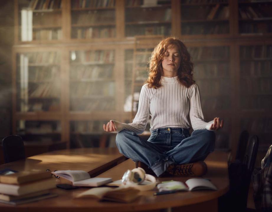 Woman does a yoga pose on top of a desk.
