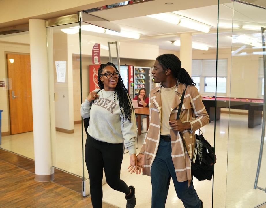 Two students walk through residence hall doorway