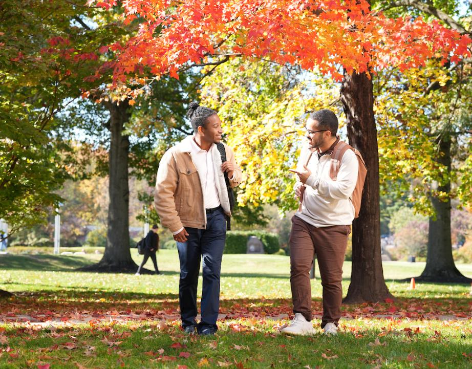 Two male students walk across campus while talking