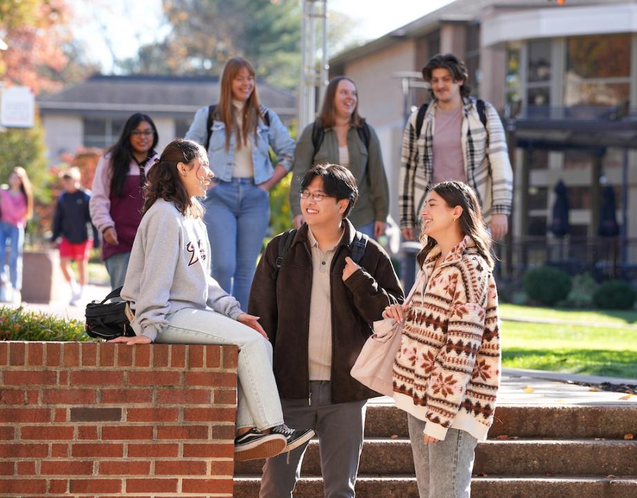 Group of three students sits outside and talks