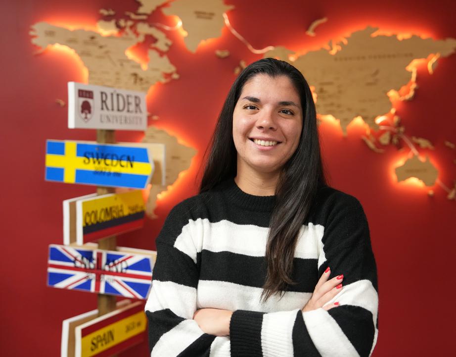 Student posing in front of wall of Office of International Education