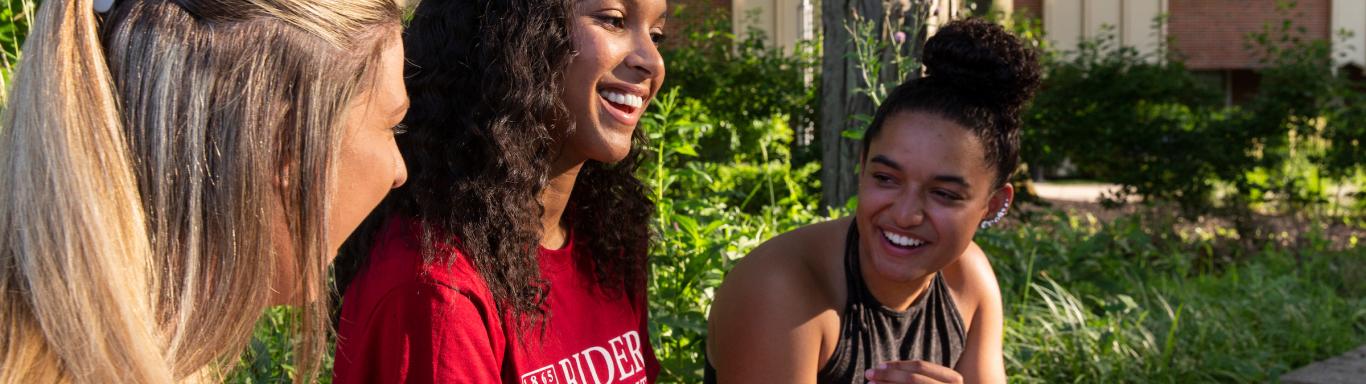 Three students talk and laugh together