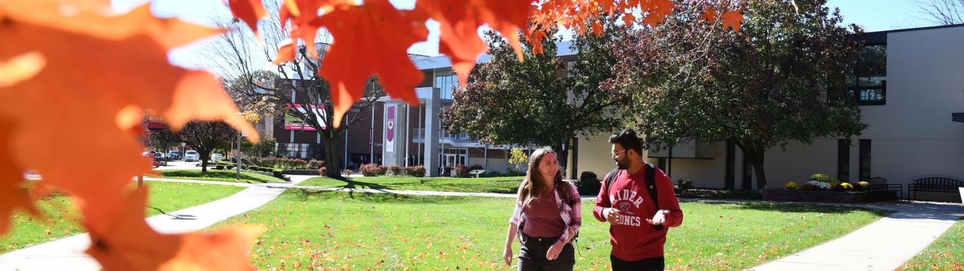 Two students walk on campus in fall