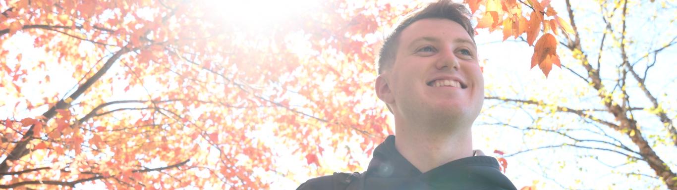 Student walks under fall leaves