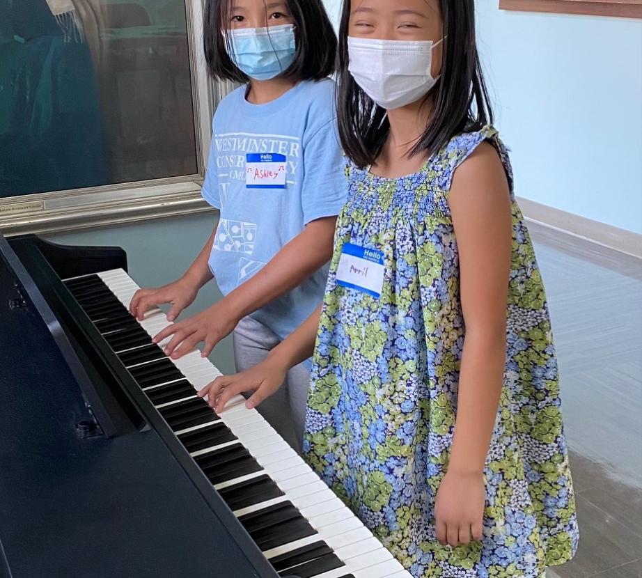 Two masked Piano Camp students at a digital piano
