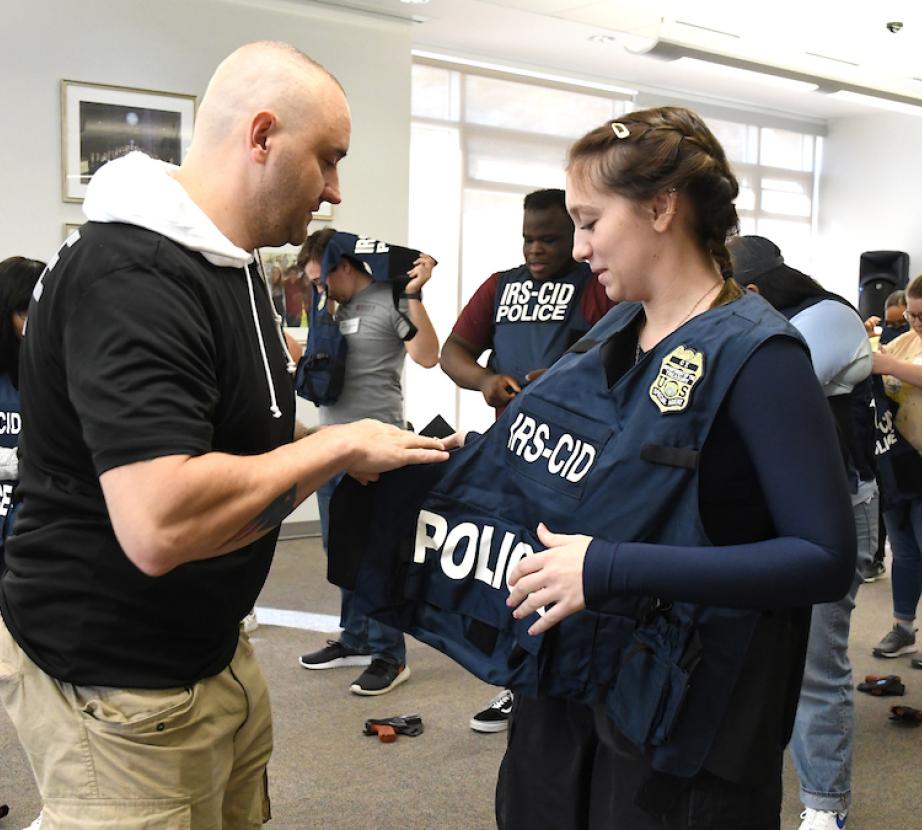 special agent helps a student put on a protective vest during Citizen Academy program
