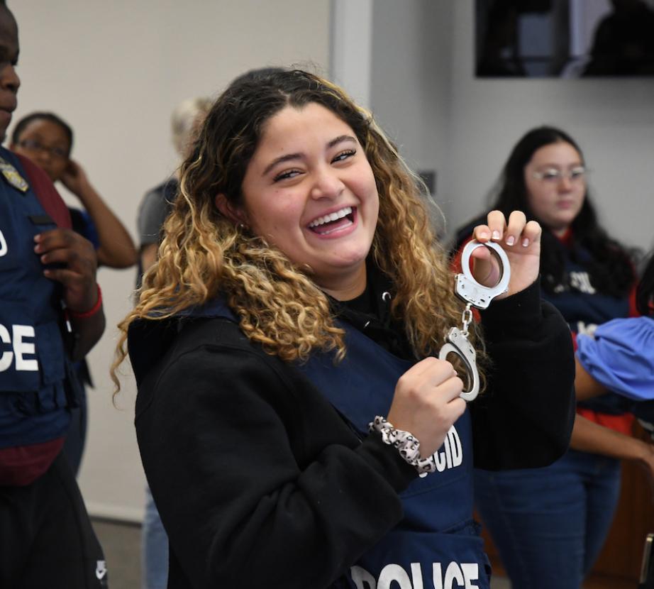 student holds up handcuffs during Citizen Academy program