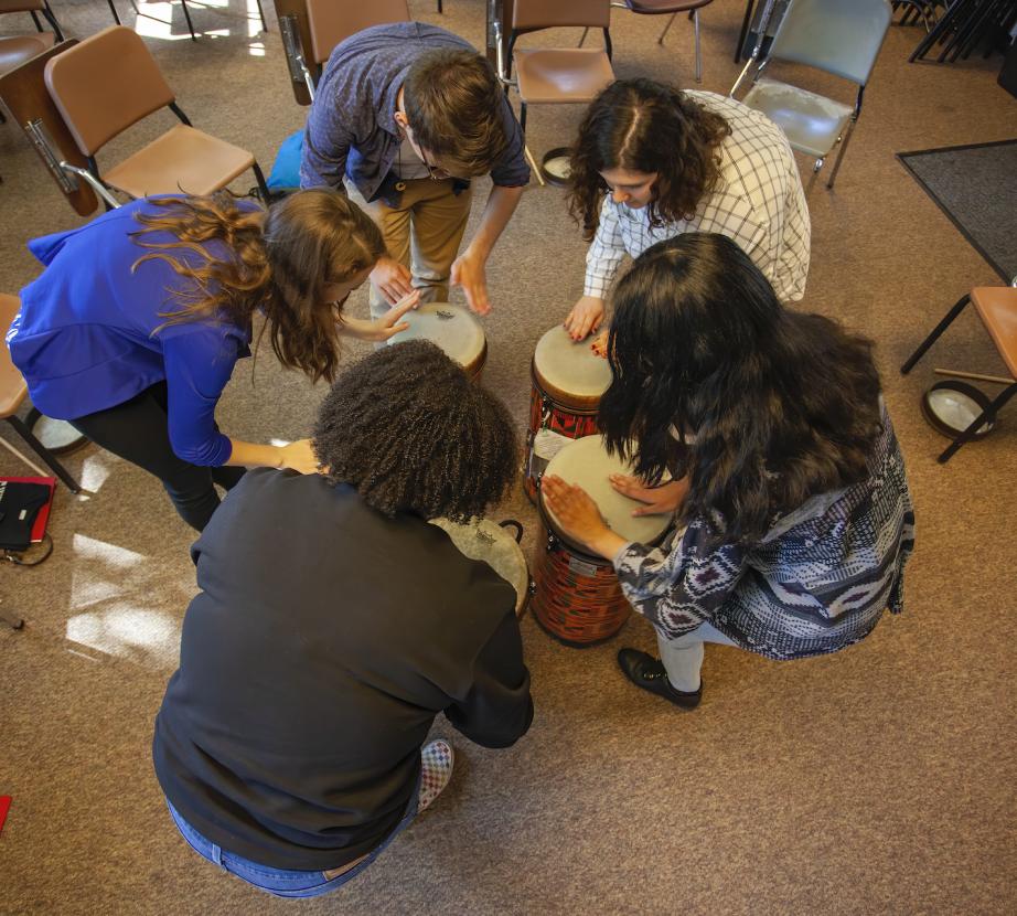 Faculty and students playing bongos in classroom