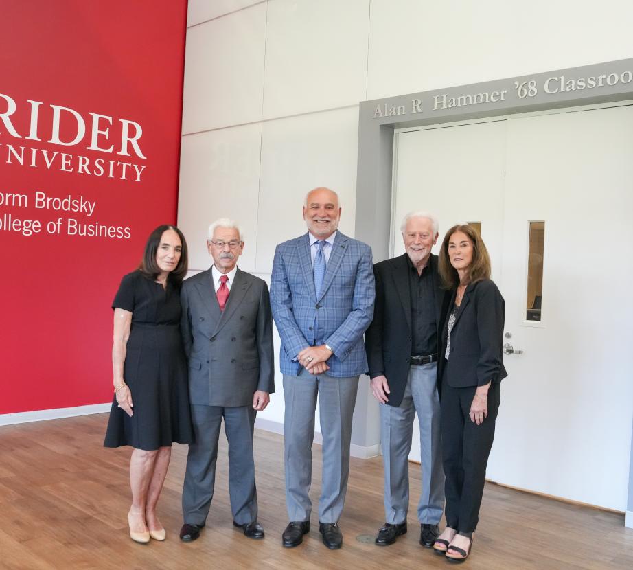 The Canastras and Hammers pose in front of the Alan R. Hammer ’68 Classroom with President John R Loyack