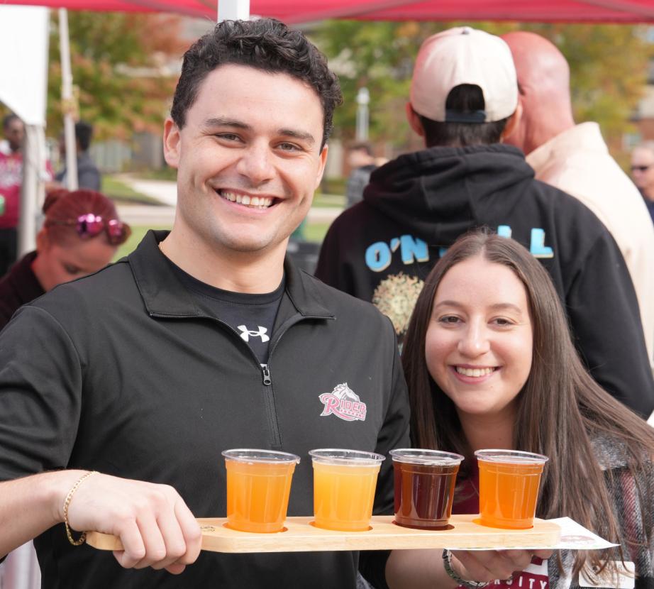 Two people pose with a drink flight