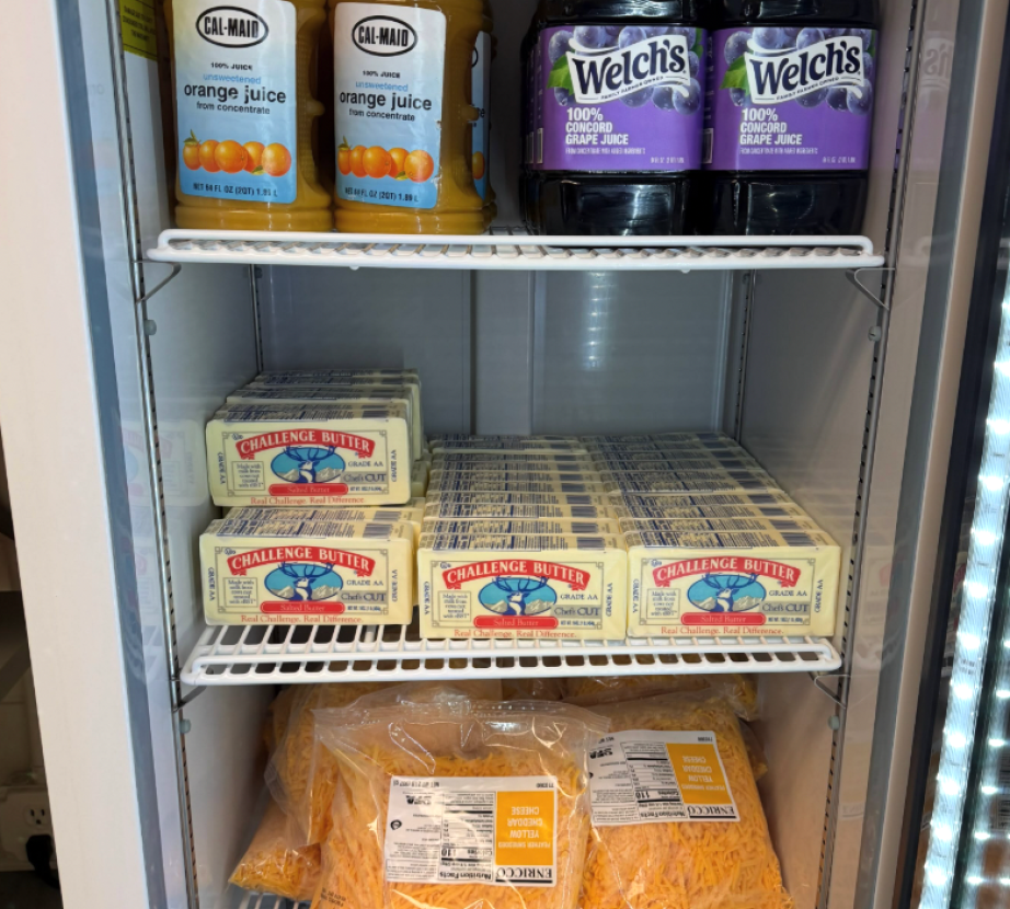 Shelves in the pantry featuring orange and grape juice, butter and shredded cheese