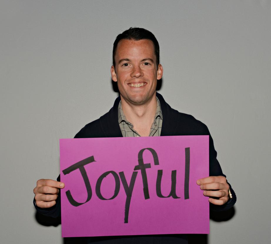 Man holding sign saying "Joyful"