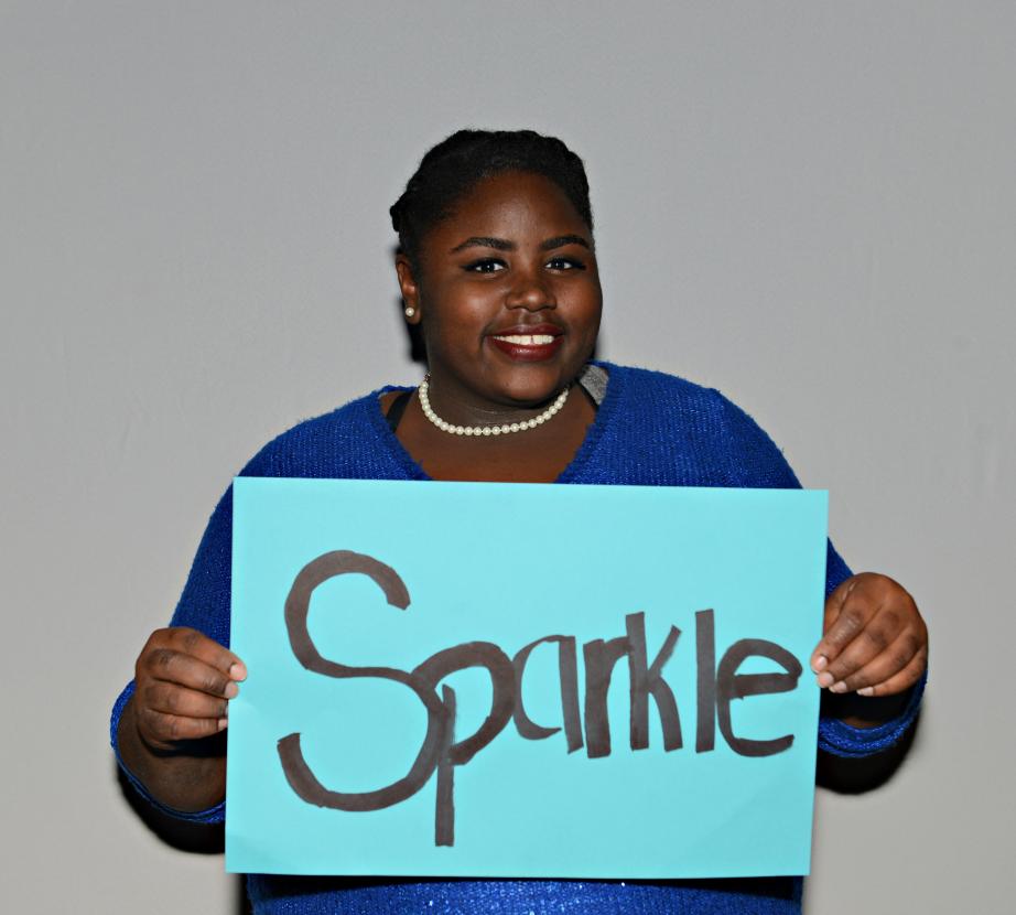 Woman holding sign saying "Sparkle"
