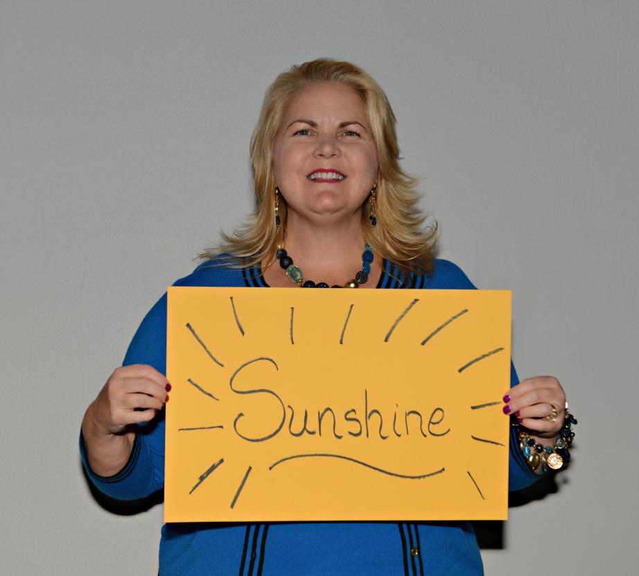 Woman holding sign saying "Sunshine"