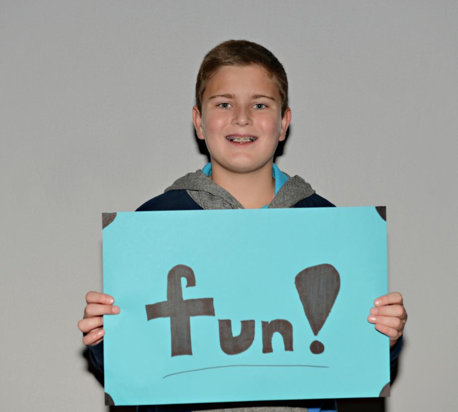 Boy holding sign saying "fun!"