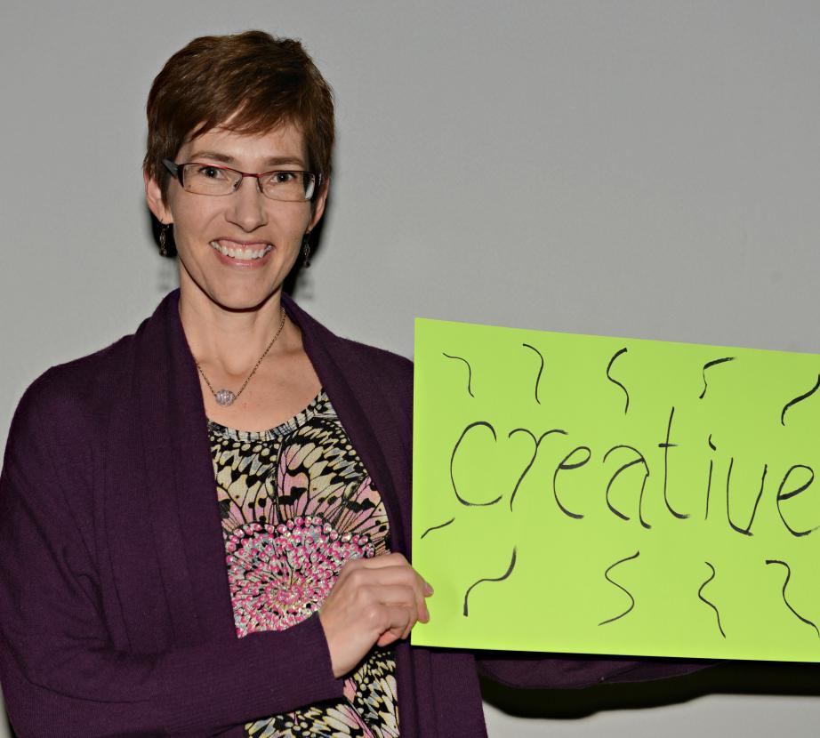 Woman holding sign saying "Creative" 
