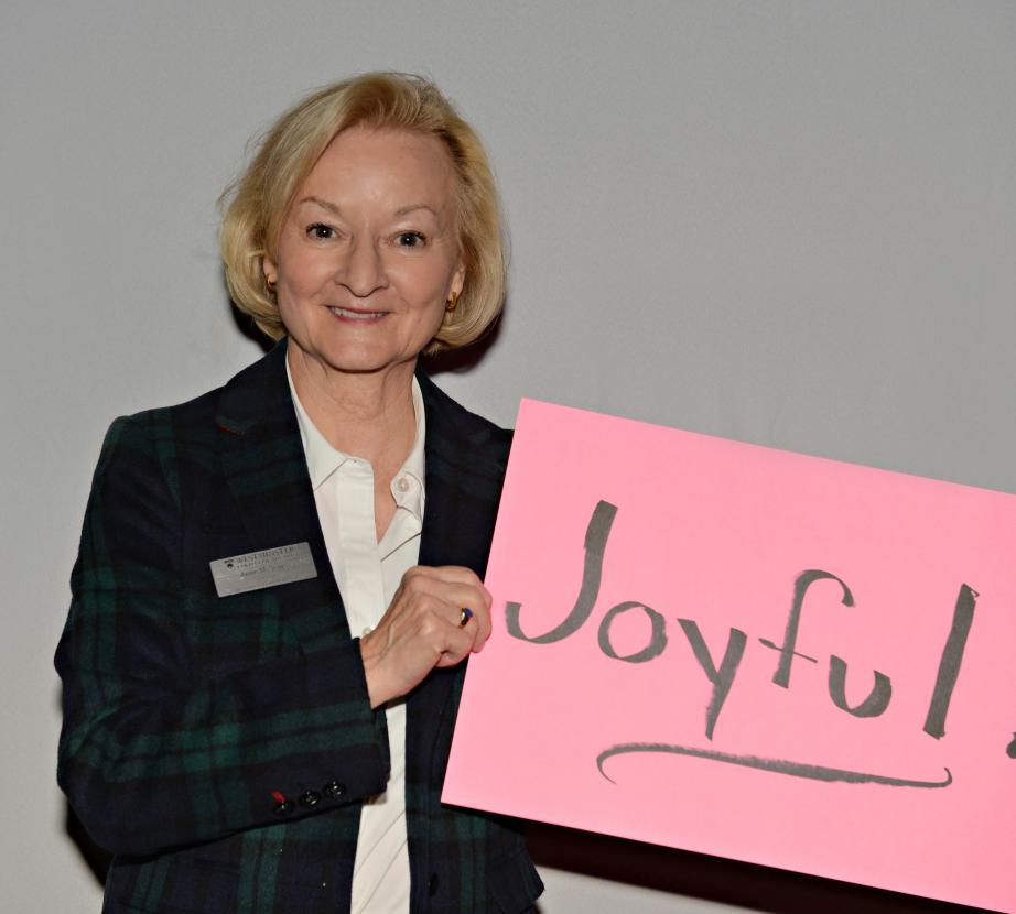 Woman holding sign saying "Joyful!"