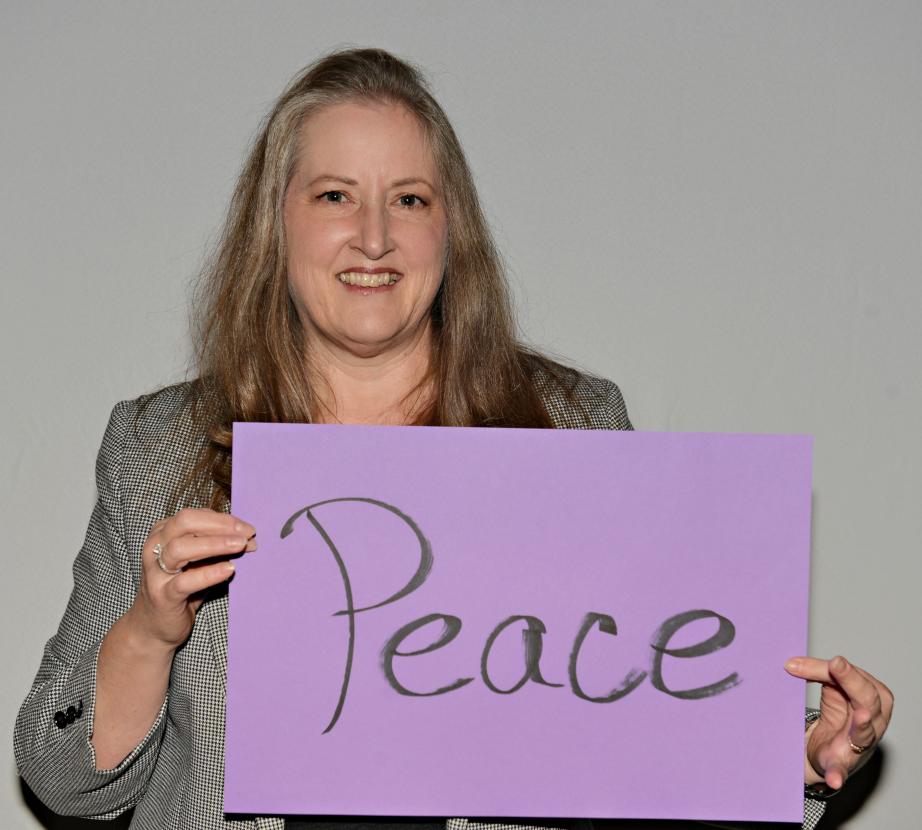 Woman holding sign saying "Peace"