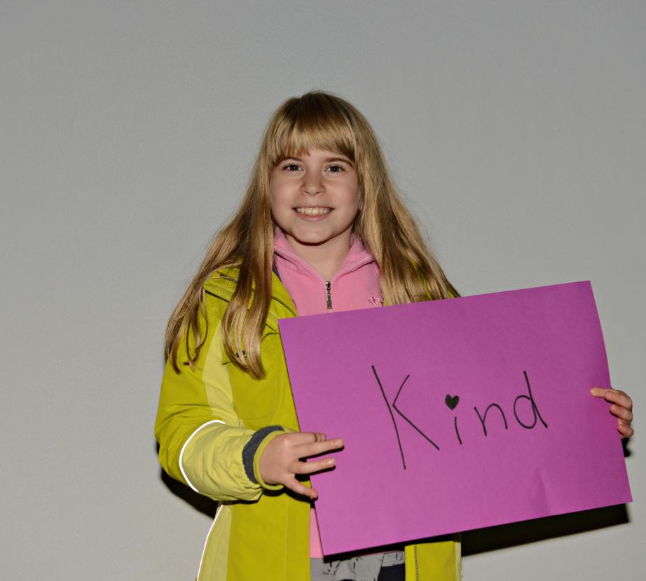 Girl holding sign saying "KInd"