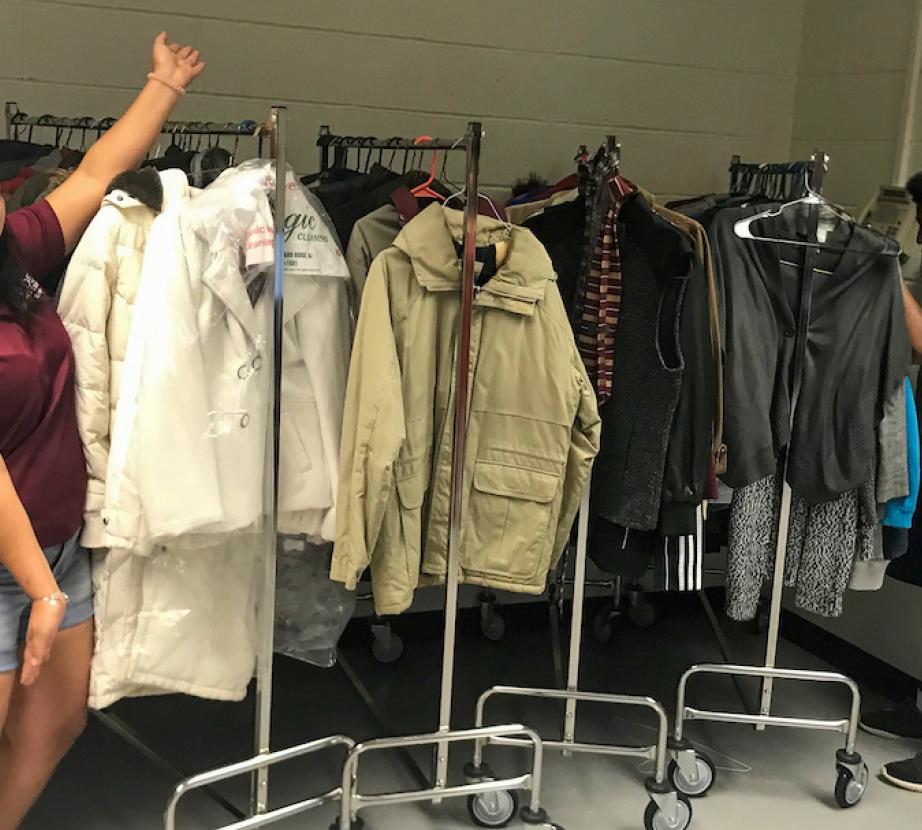 Student poses by racks of clothes.