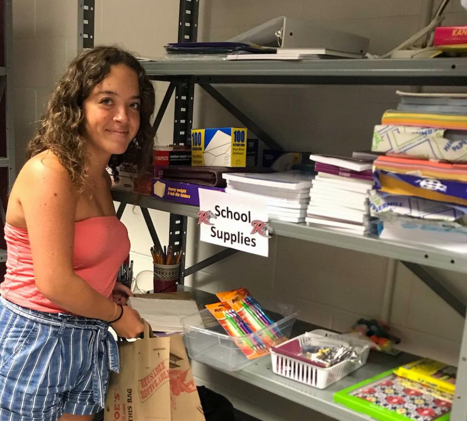 Student poses by school supplies.