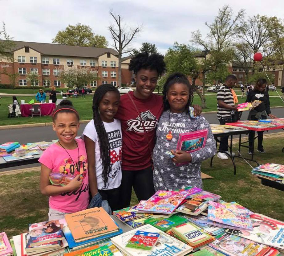Student poses with kids at book fair.