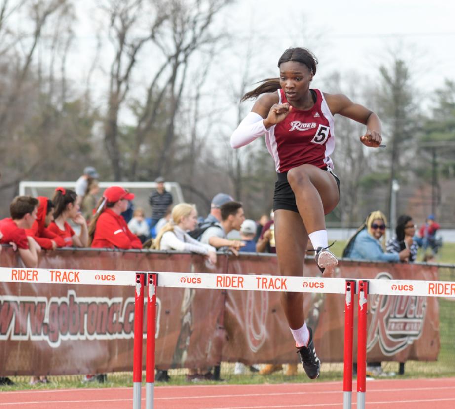 Sprinter jumps hurdles at meet.