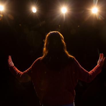 Student stands on stage in front of spotlights