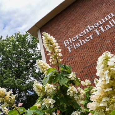 Education building with flowers in front of it.