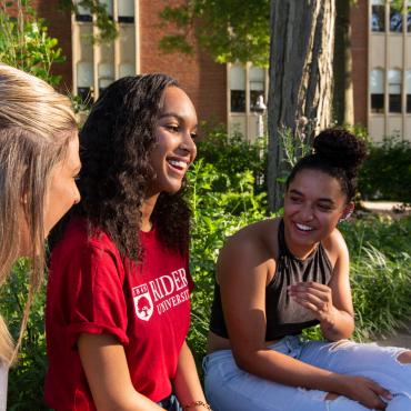 Three students talk and laugh together