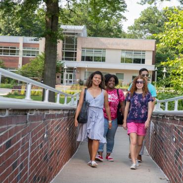 Four students walk across campus