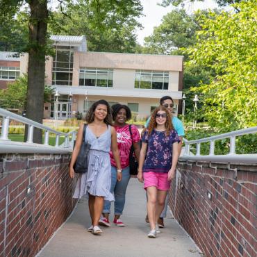 Four students walk to Moore Library