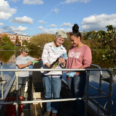 Student and faculty on a boat on Centennial Lake doing research